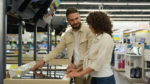 Happy couple choosing discounted induction stovetop in electronics store Stock Footage 317728583