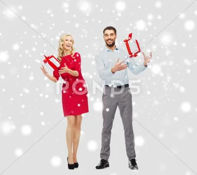 Happy couple with christmas gift boxes over snow Stock Photos