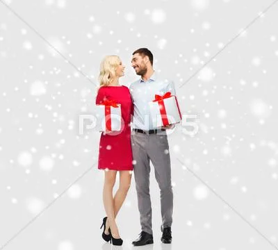Happy couple with christmas gift boxes over snow Stock Photos