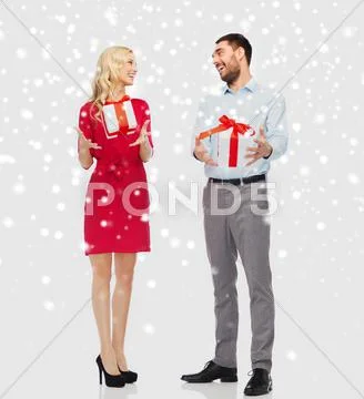 Happy couple with christmas gift boxes over snow Stock Photos