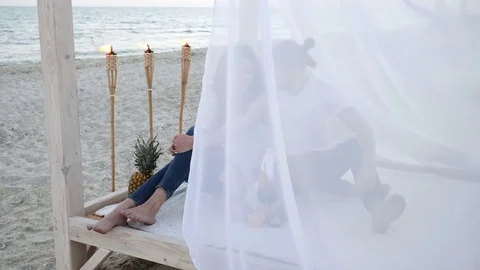 Happy couple with cocktails, have fun, bungalow with white cloth, an exotic Stock Footage