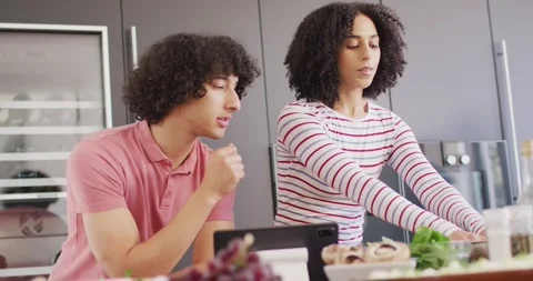 Happy couple cooking dinner and using tablet in kitchen together Stock Footage 344103555