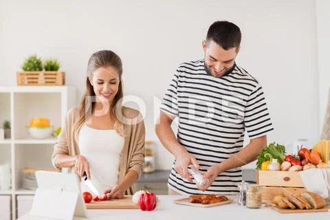 Happy couple cooking food at home kitchen Stock Photos