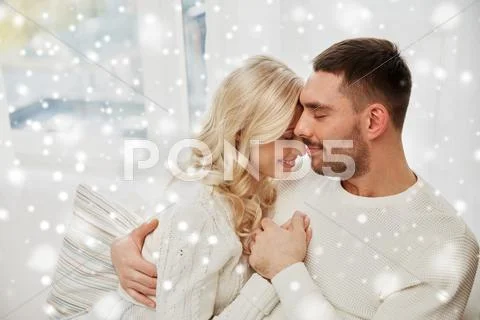 Happy couple covered with plaid on sofa at home Stock Photos