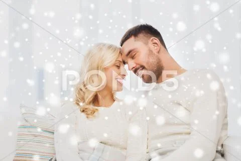 Happy couple covered with plaid on sofa at home Stock Photos