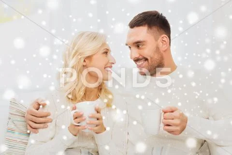 Happy couple with cups drinking tea at home Stock Photos