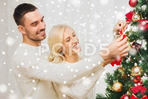 Happy couple decorating christmas tree at home Stock Photos
