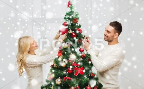 Happy couple decorating christmas tree at home Stock Photos