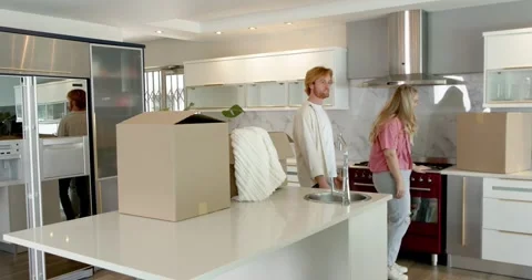 Happy couple doing a house tour, walking through kitchen, discussing interior, Stock Footage 317367192