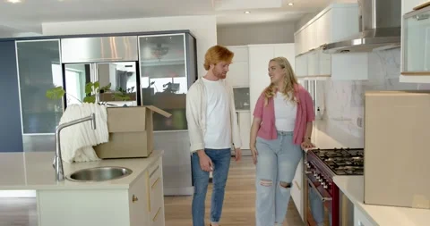 Happy couple doing a house tour, walking through kitchen, discussing interior, Stock Footage 317367221