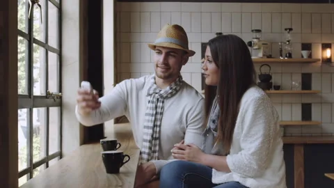 Happy couple doing selfie or taking picture with smartphone in a cafe, steadicam Stock Footage 199632158