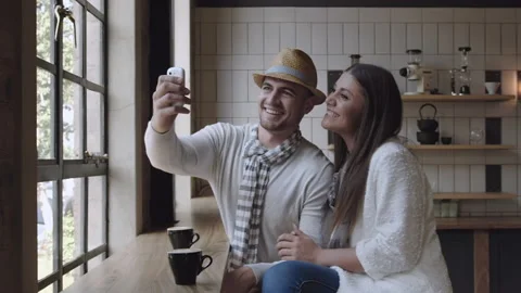Happy couple doing selfie or taking picture with smartphone in a cafe, steadicam Stock-Footage 199632263