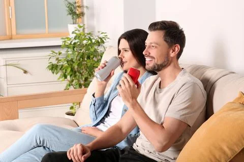 Happy couple drinking beverages on sofa indoors Stock Photos