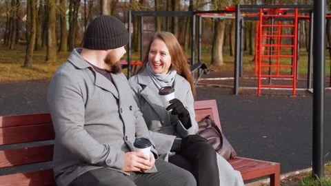 Happy couple drinking coffee and talking on park bench Stock Footage 326149059
