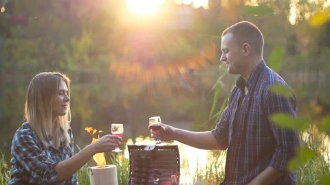 Happy couple drinks vine at sunset evening picnic weekend near the lake Stock Footage 81756632
