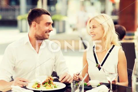 Happy couple eating dinner at restaurant terrace Stock Photos