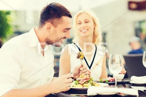 Happy couple eating dinner at restaurant terrace Stock Photos