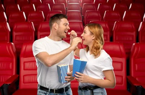 Happy couple eating popcorn at movie theatre Stock Photos