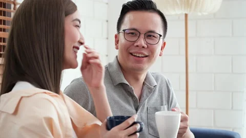 Happy couple enjoying a casual conversation over coffee in a cozy home Stock Footage 292606953