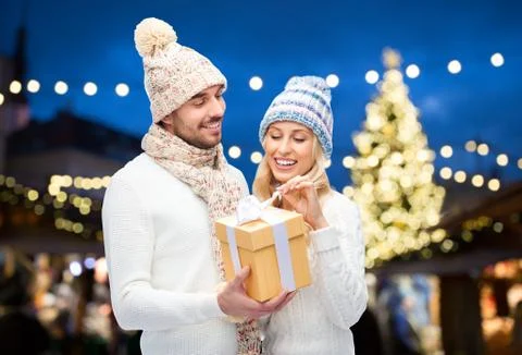 Happy couple with gift box over christmas lights Fotos Stock