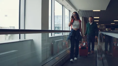 Happy couple going to the plane with red suitcases in airport. Woman in Stock Footage 108869059