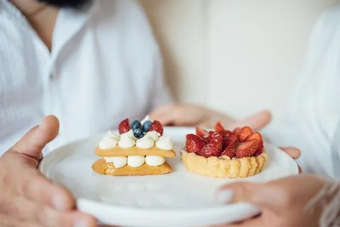 Happy couple having breakfast in bed with delicious cookies with strawberries on Stock Photos