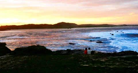 Happy couple having date and looking at the blue sea with yellow pink sky Stock Footage 103292396