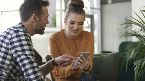 Happy couple having fun at cafe browsing smartphone together Stock Footage 70807912