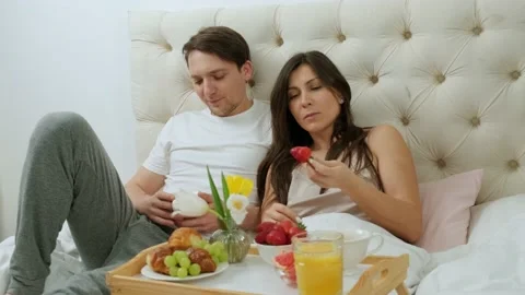 Happy couple having fun, eating breakfast in bed and drinking a cup of coffee. Stock Footage 147270776
