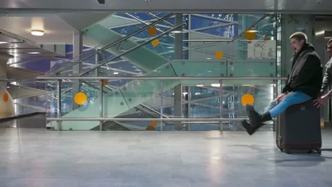 Happy couple having fun, riding a suitcase at the airport. Spouses fooling Stock Footage 170601405