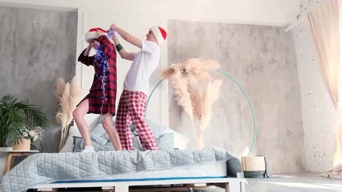 Happy couple having fun standing on the bed untangling tangled garland Stock Footage 144957910