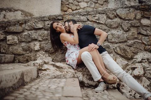 Happy couple having fun while sitting on stone street Stock Photos