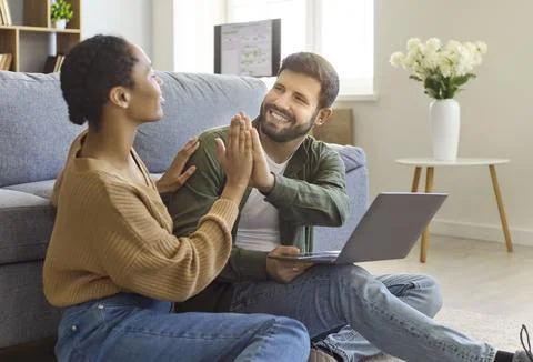 Happy couple high five while using laptop at home, teamwork and online planning Stock Photos