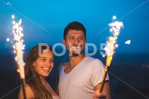 The happy couple hold a firework sticks. evening night time Stock Photos