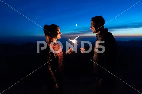 The happy couple holding firework sticks on the mountain background Stock Photos