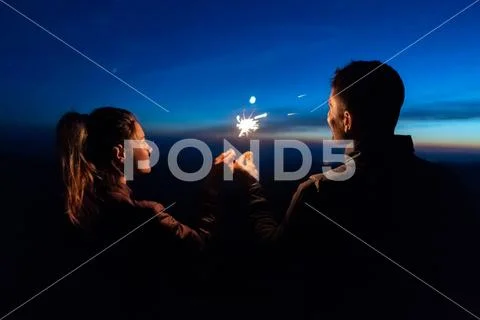 The happy couple holding firework sticks on the sunrise background Stock Photos