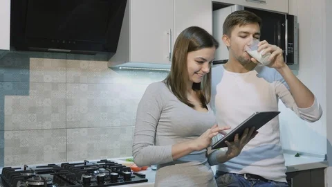 Happy couple at home in kitchen using tablet together Stock Footage 86112716