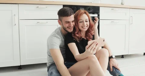 Happy couple at home in kitchen using smartphone together browsing online having Stock-Footage 103311083