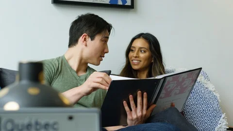 Happy couple interacting with each other while looking at their album at home Stock Footage 111970623