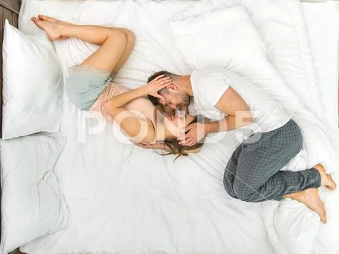 The happy couple kiss in the bed. View from above Stock Photos