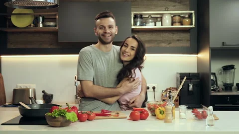 Happy couple at the kitchen. Hugging, smiling and looking at camera. Stock Footage 100303192