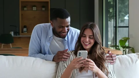 Happy Couple Laughing Together While Using Smartphone on Sofa at Home 스톡 동영상 333539125