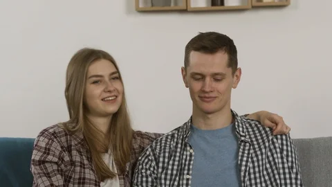Happy couple laughing while embracing on couch and watching tv Stock-Footage 124950649