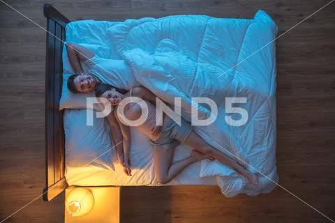 The happy couple lay on the bed. evening night time. view from above Stock Photos