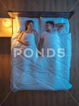 The happy couple lie on the bed. evening night time. view from above Stock Photos