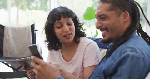 Happy couple in living room using laptop and talking, with her wheelchair in Stock Footage 342017626