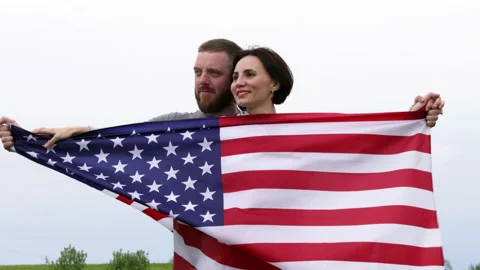 Happy couple looking in one side and holding in hands big American flag Stock Footage 154578708
