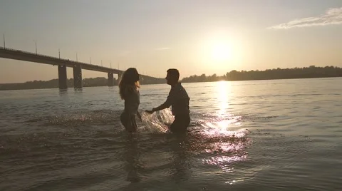 Happy couple in love playing in the river, hugging and kissing each other Stock Footage