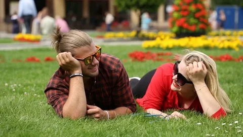Happy couple lying on the grass and chatting with each other Stock Footage 77475976