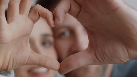 Happy couple making heart shape with hands gesturing romantic commitment 库存影片 103514236